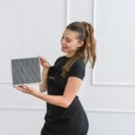 Frau mit dekorierten Haaren, die stolz ein Produkt hält und dabei lächelt