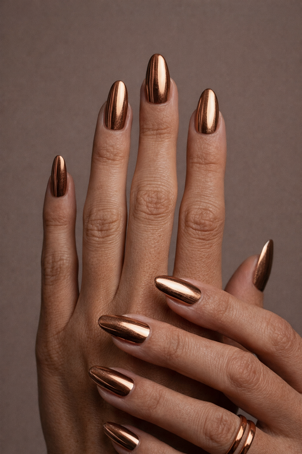 Hand mit langen kupferfarbenen Chrom Nägeln