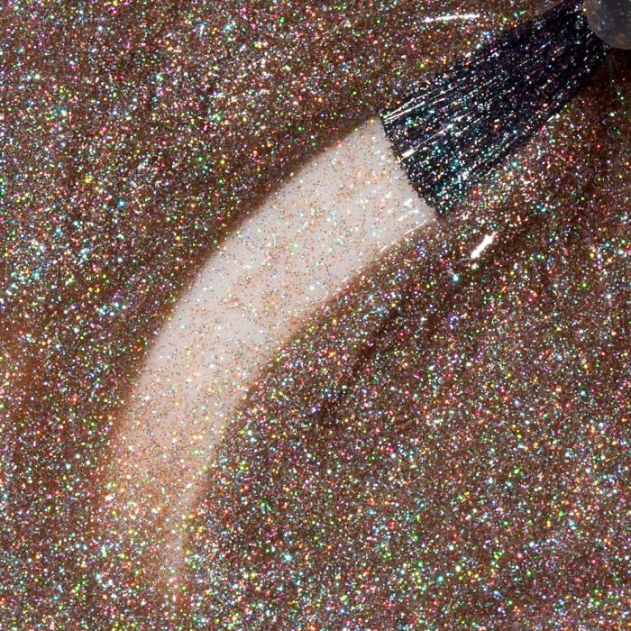 Nahaufnahme von rosé-bronzefarbenem Glitzer-Nagellack mit holografischen Partikeln und sichtbarem Pinselstrich