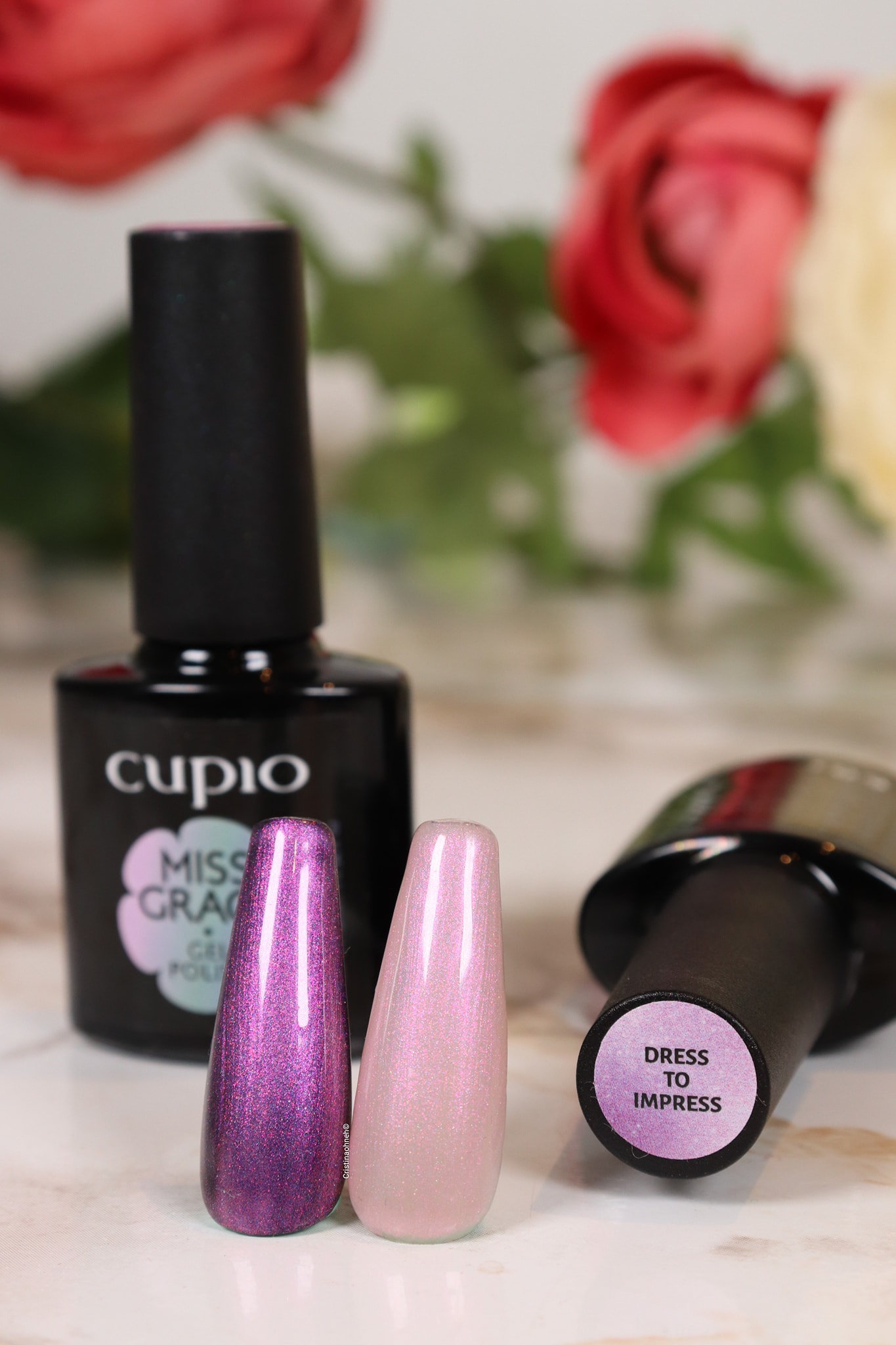 274063959_10221077893199769_3988128533777659008_n Cupio Gel-Nagellack mit zwei Farbmuster in Lila und Rosa, Hintergrund mit Blumen.