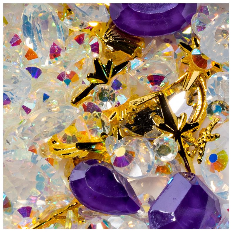 Nahaufnahme von glitzernden Schmucksteinen in verschiedenen Farben, darunter goldene Ornamente und lila Steine.