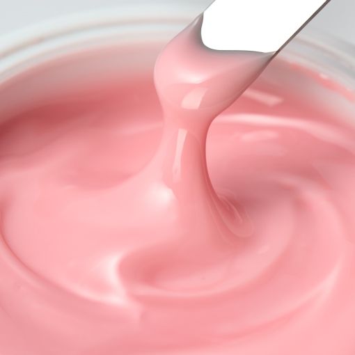 Nahaufnahme einer rosa Creme, die mit einem Spachtel aufgetragen wird.