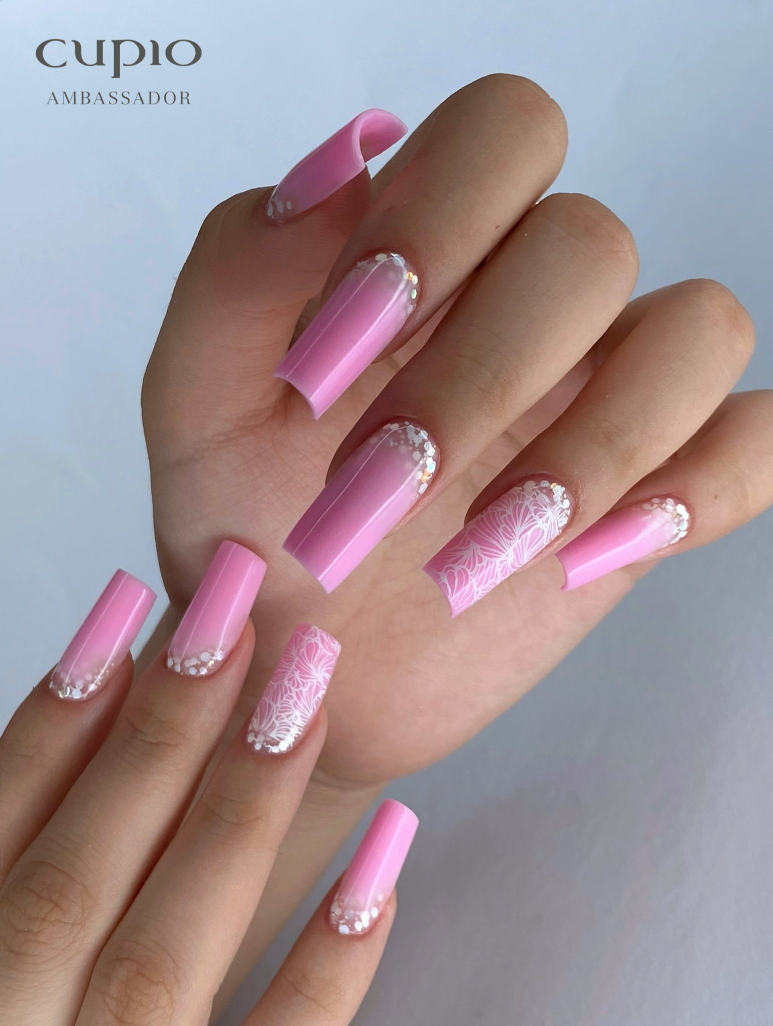 Maniküre mit rosa Nägeln, verziert mit einem floralem Muster und Perlen