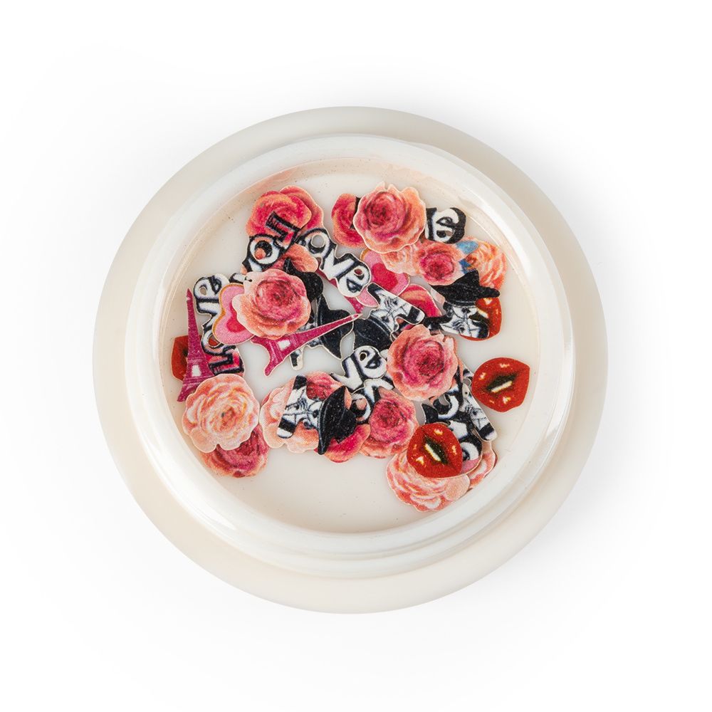 Buntes Set aus Nagelkunst-Dekorationen mit Rosenmotiven und Schriftzügen in einem Behälter