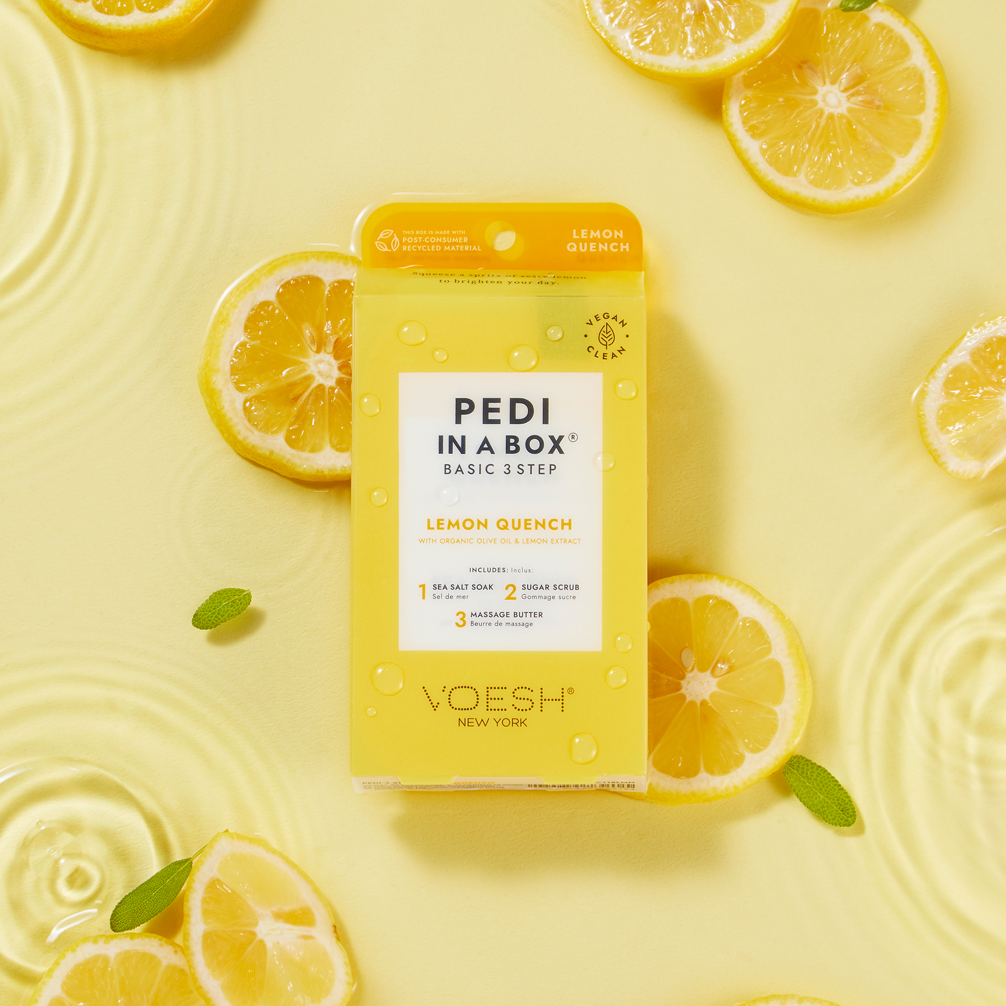 VOESH Pedi in a Box Basic 3 Step Lemon Quench Pediküre-Set auf gelbem Hintergrund mit Zitronenscheiben und Wassertropfen