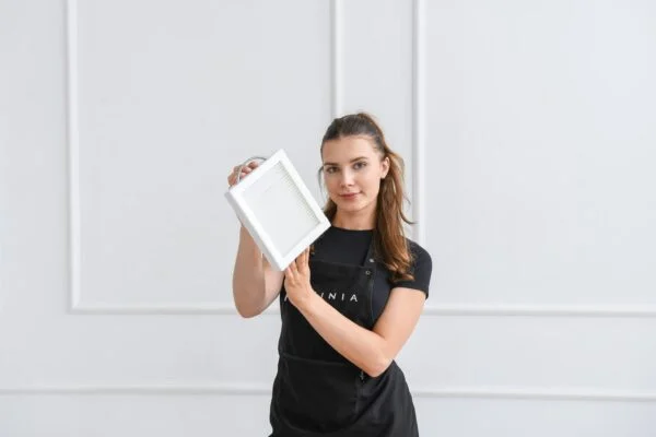 Frau präsentiert einen modernen Bilderrahmen in einem hellen Raum