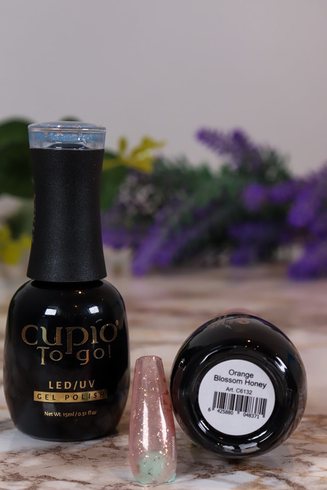 274905490_10221143225673040_1249762768024149401_n Cupio To Go! Gel Nagellack in der Farbe Orange Blossom Honey mit einem Nagel in rosa und mintfarbenem Glitzer.