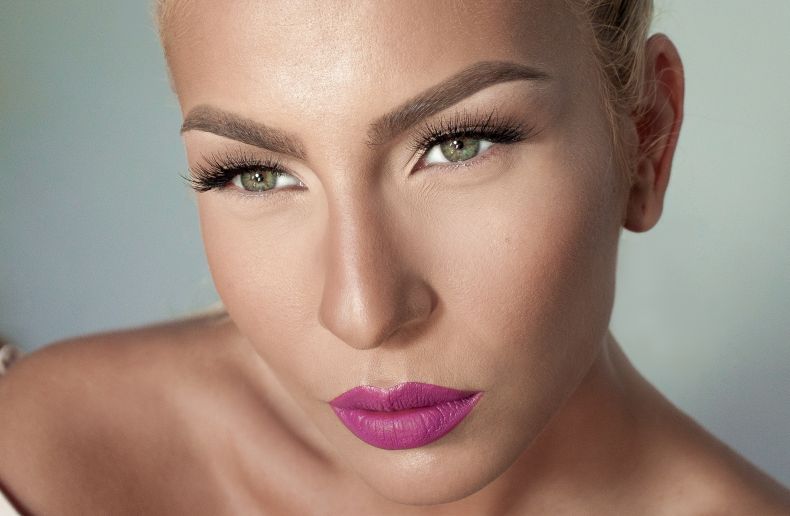 Porträt einer Frau mit grünen Augen und pinkem Lippenstift