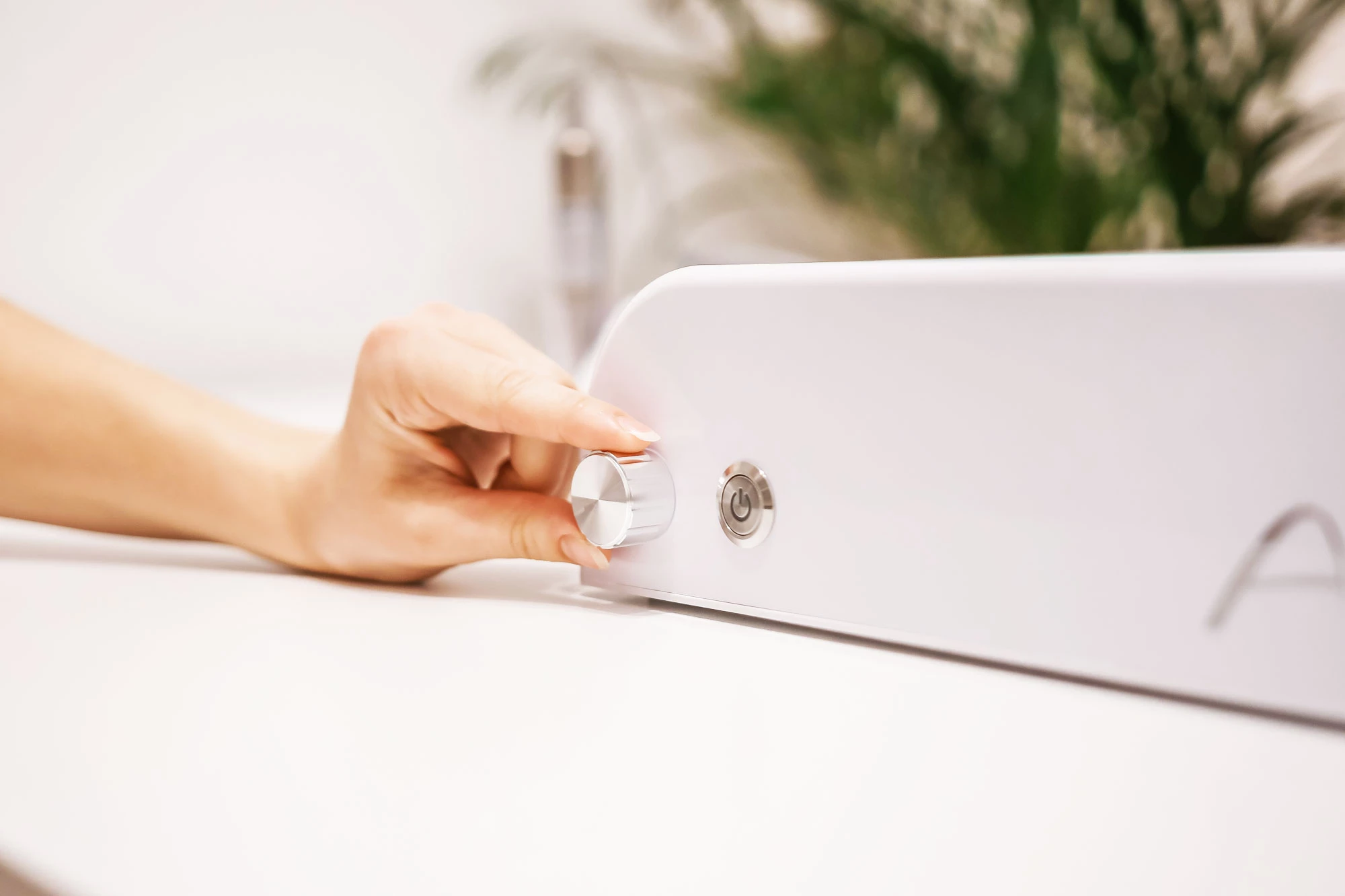 Mobile-plus-2b Nutzer stellt die Lautstärke an einem modernen weißen Gerät mit Drehknopf ein.