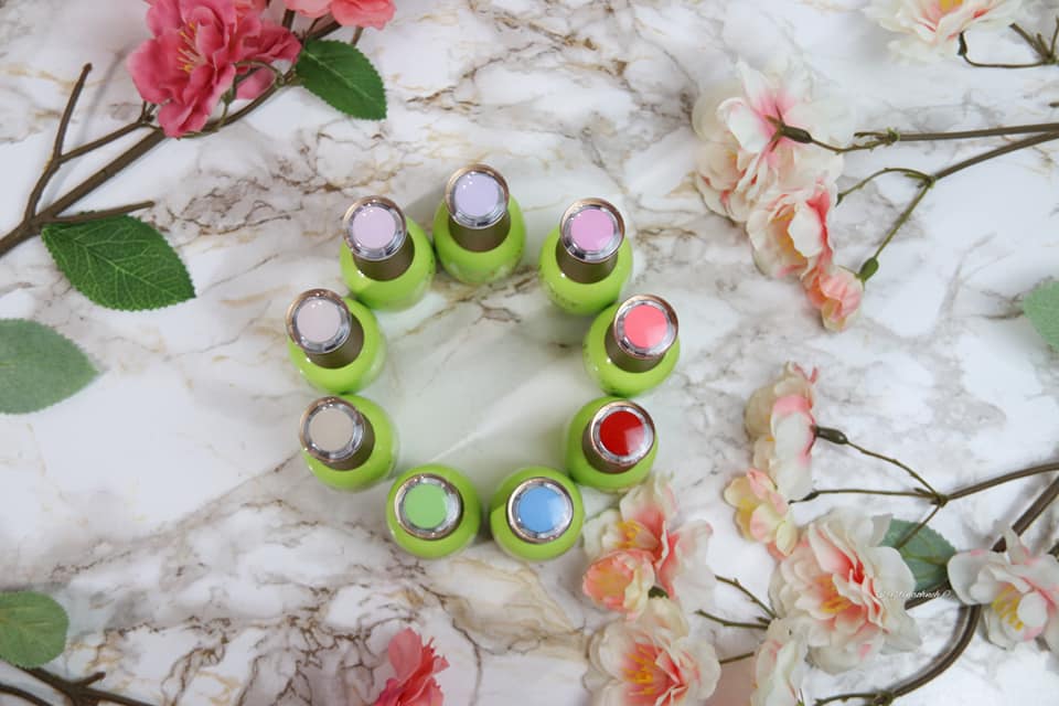 156868733_10219176452104930_6733805142853425914_n Bunte Nagellackflaschen im Kreis angeordnet, umgeben von floralen Elementen