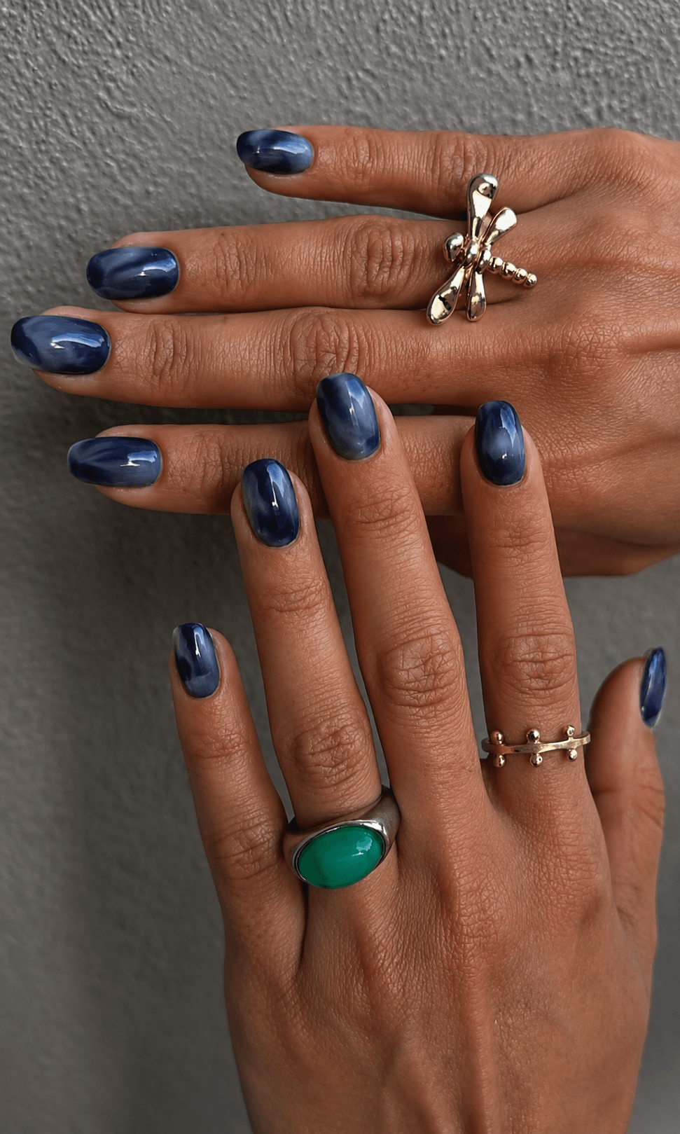 Nahaufnahme von Händen mit blau marmorierter Maniküre und stilvollen Ringen als Produktdarstellung für Nail-Art oder Press-on-Nägel