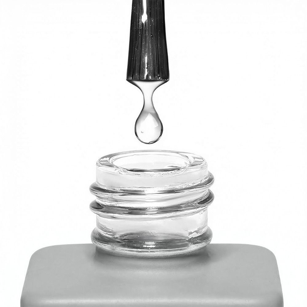 Nahaufnahme einer transparenten Pipette, aus der ein klarer Tropfen in die Öffnung eines leeren Glasfläschchens fällt