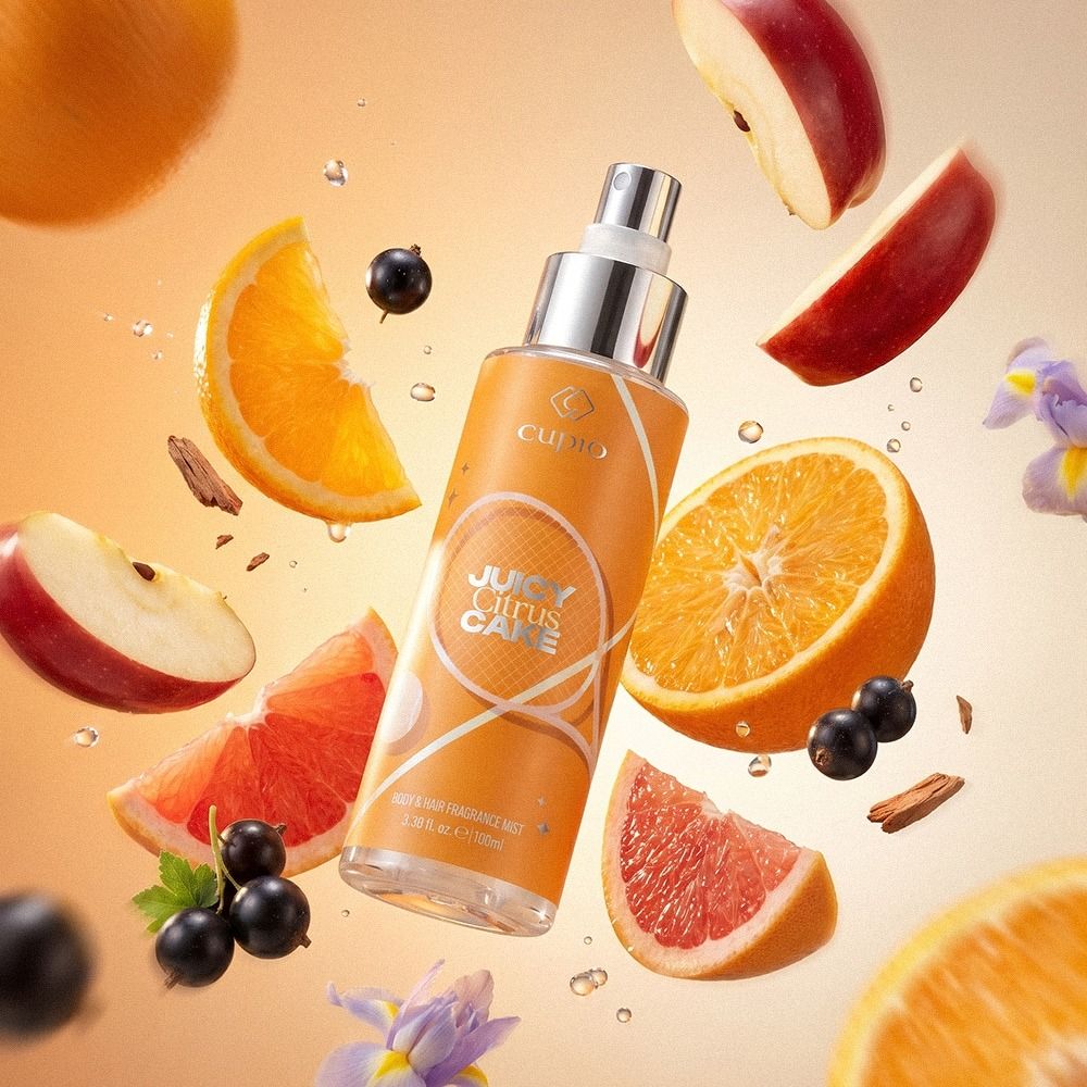 Produktbild von Cupio Juicy Citrus Cake Body & Hair Fragrance Mist, umgeben von Orangenscheiben, Grapefruit, Apfelstücken und schwarzen Johannisbeeren