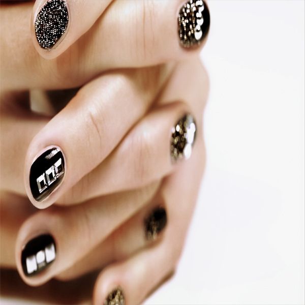Hände mit schwarzem Nageldesign und glitzernden Akzenten