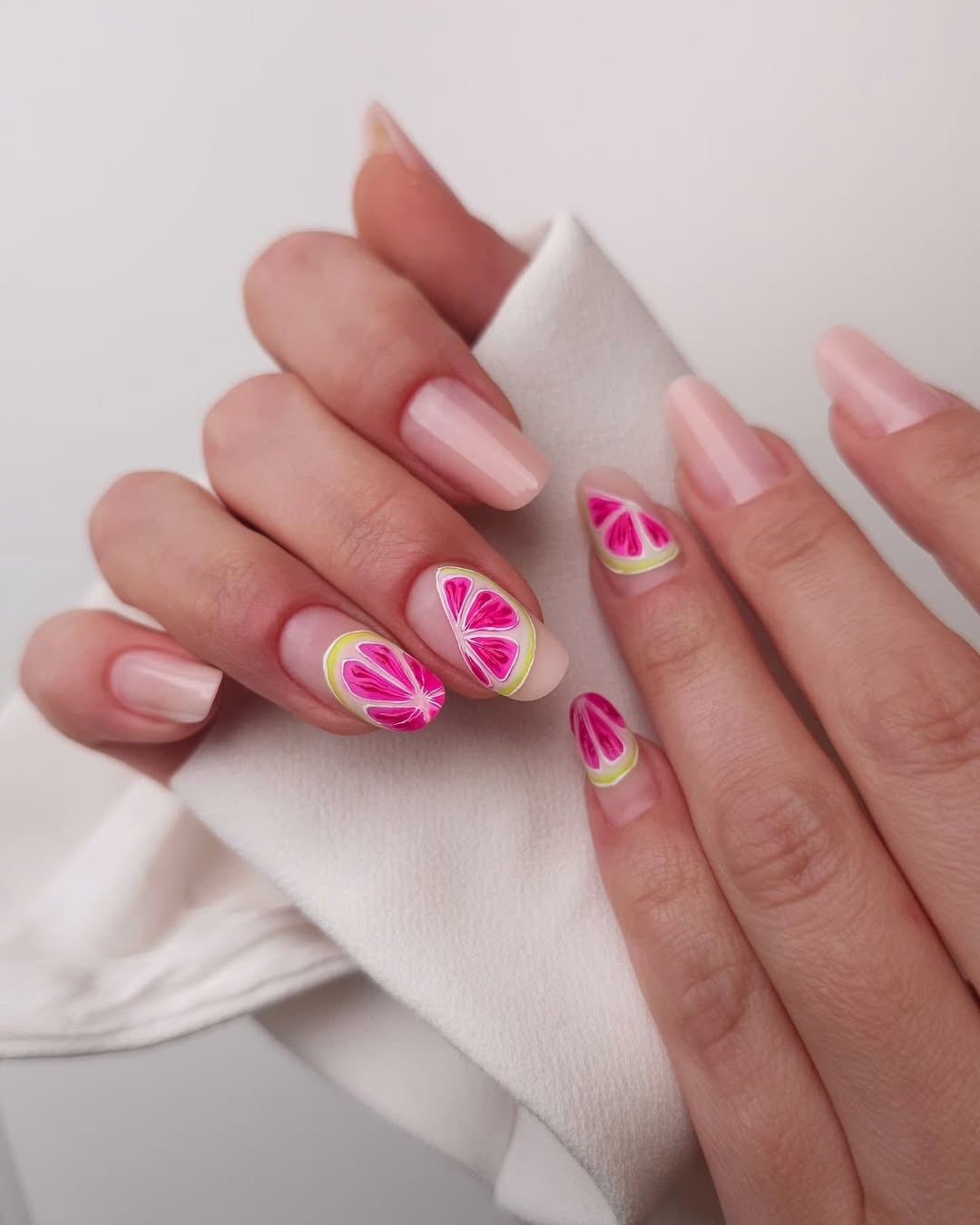 Hände mit Nageldesigns in Zitrusfrüchte-Optik, pinke und gelbe Farben