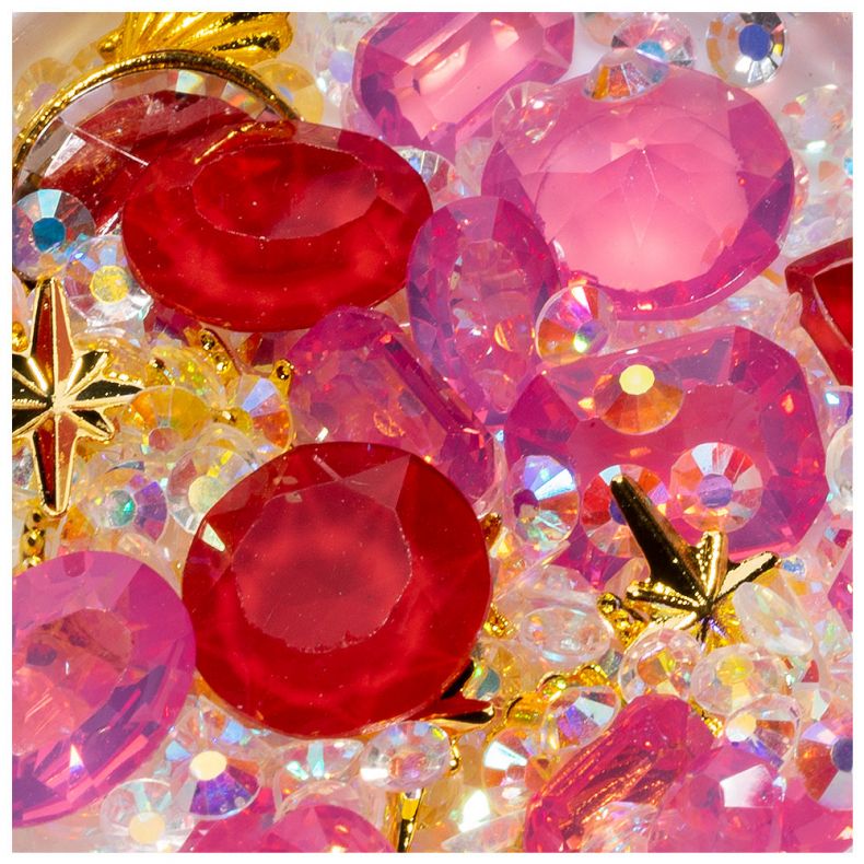 Stapel bunter Schmucksteine in rot, pink und transparent mit goldenen Akzenten