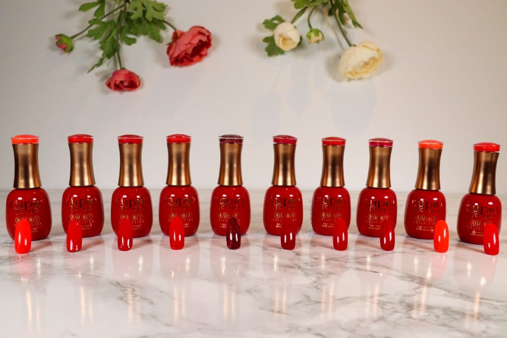 319320705_1796478377399318_3028581642258605230_n Verschiedene rote Nagellacke auf einem Marmortisch angeordnet