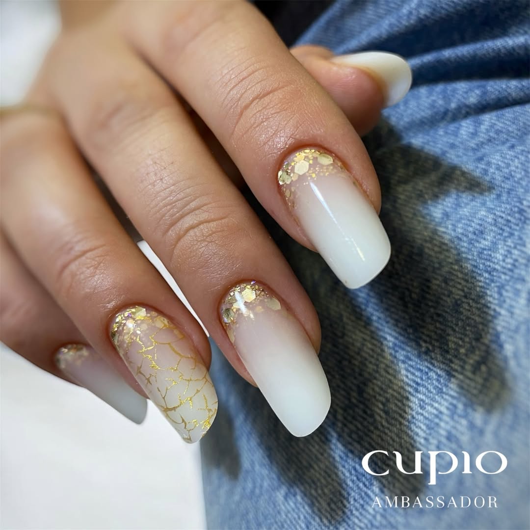 Nahaufnahme einer stilvollen Nagelmodellage mit Ombré-Effekt und goldenen Details