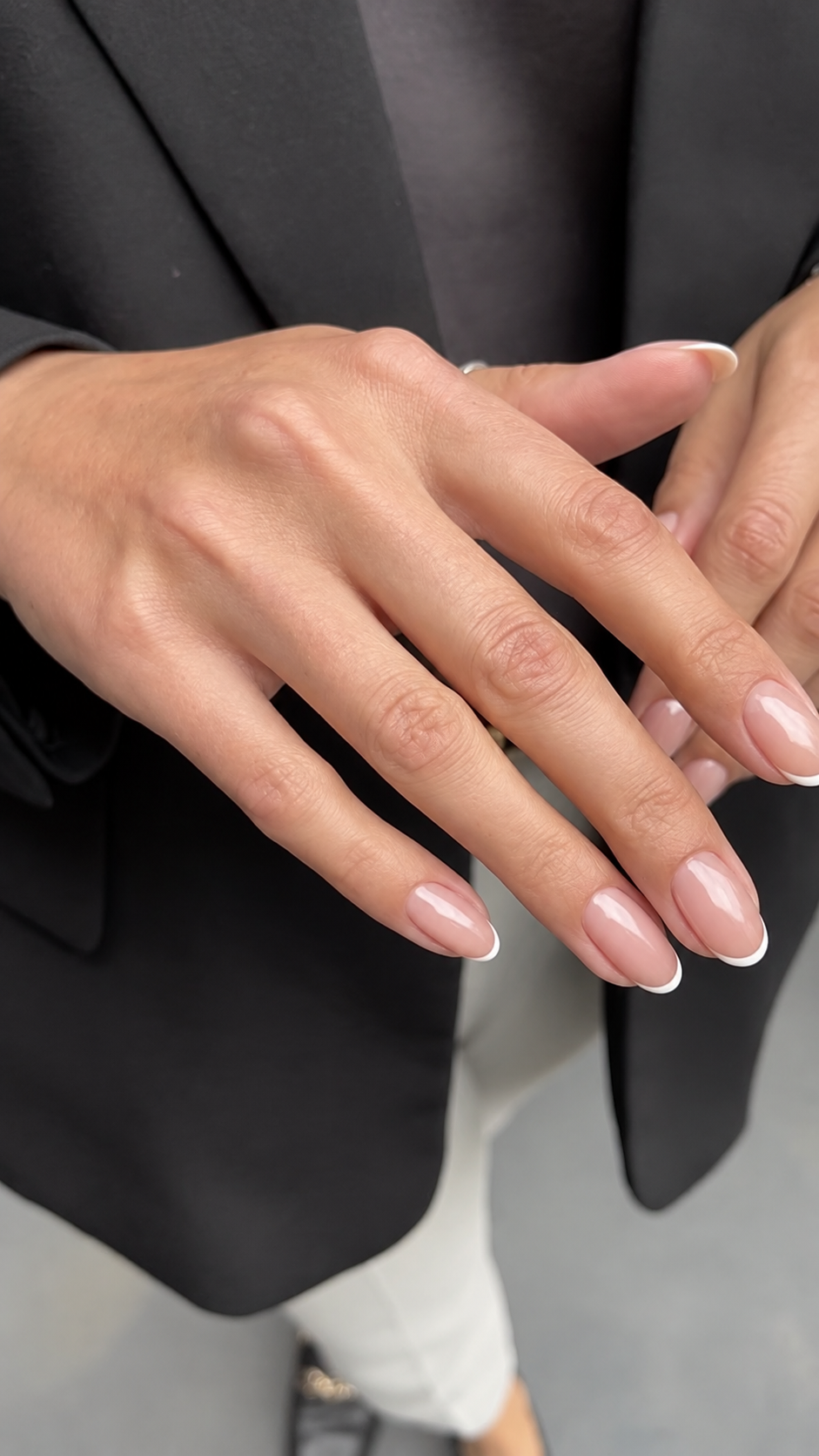 Nahaufnahme einer Hand mit gepflegter French Maniküre in Rosé und weißer Spitze auf mandelförmigen Nägeln