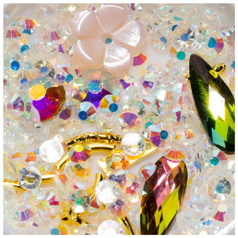 Bunte glitzernde Schmucksteine und Perlen arrangiert auf hellem Hintergrund