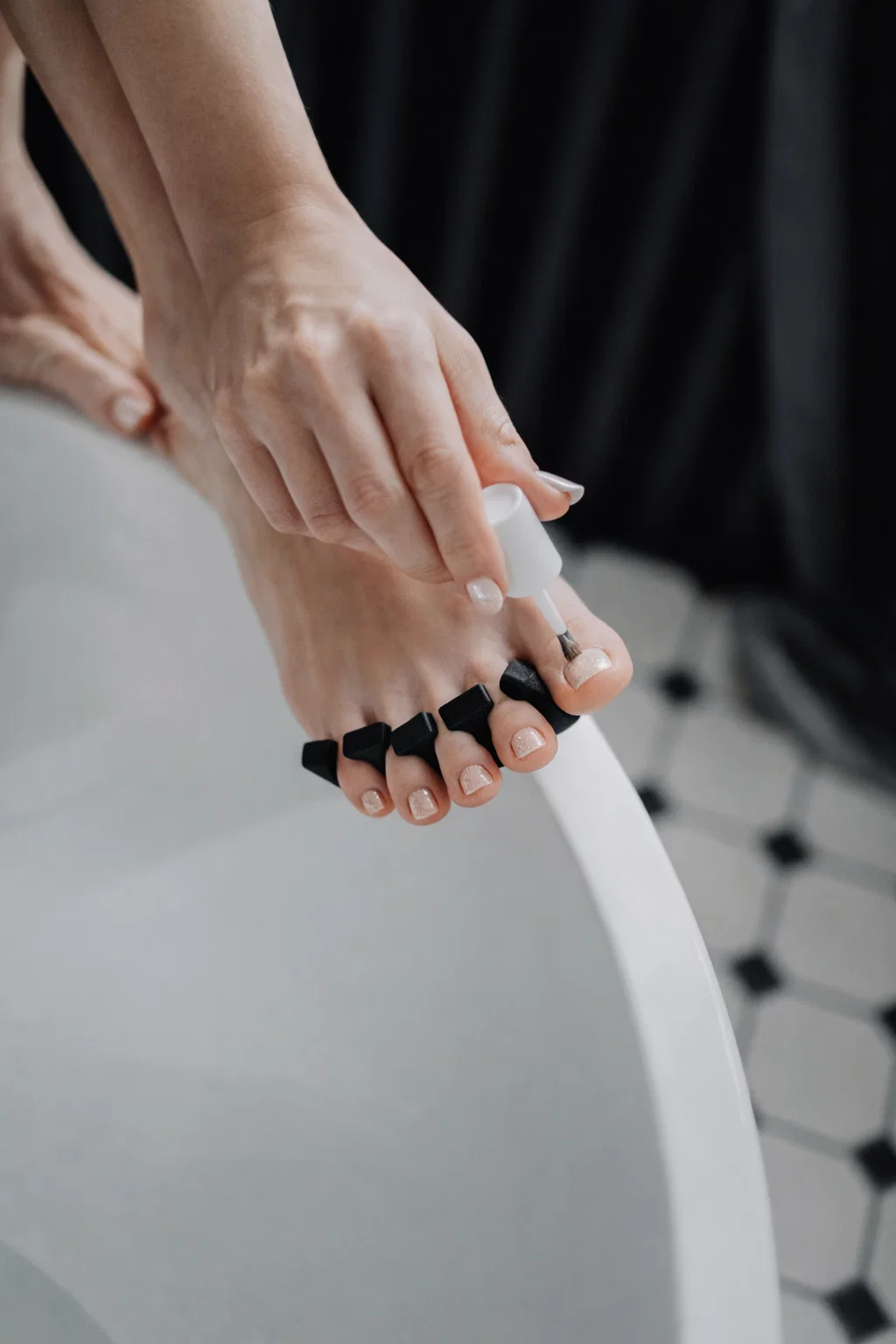 Fußpediküre mit Nagellack und schwarzen Zehenspreizern