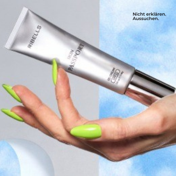 Silberne RIBELLS Skin Passport Gesichtscreme-Tube, die von einer Hand mit neon-grün lackierten Fingernägeln vor blau-weißem Hintergrund gehalten wird