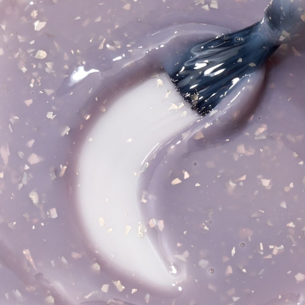 Nahaufnahme der Cupio Rubber Base Effect X Perfect Flakes Heavenly 15ml in zartem Lilaton mit schimmernden Flake-Partikeln und Pinsel für ein elegantes, selbstglättendes Nageldesign