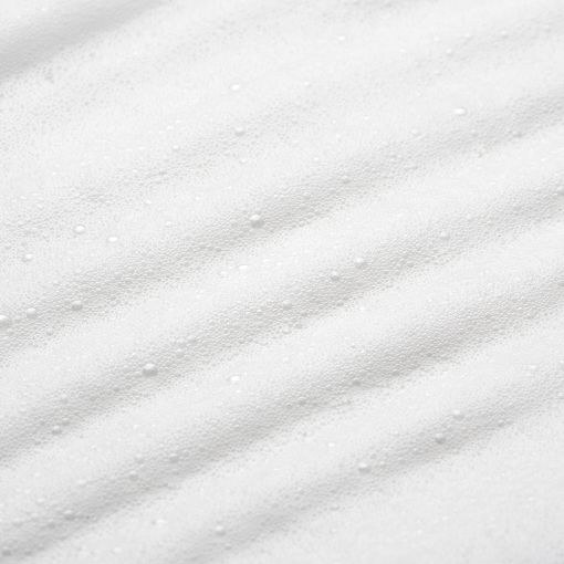 Detailaufnahme einer weißen Textilie mit leicht strukturiertem Muster und kleinen Perlen.