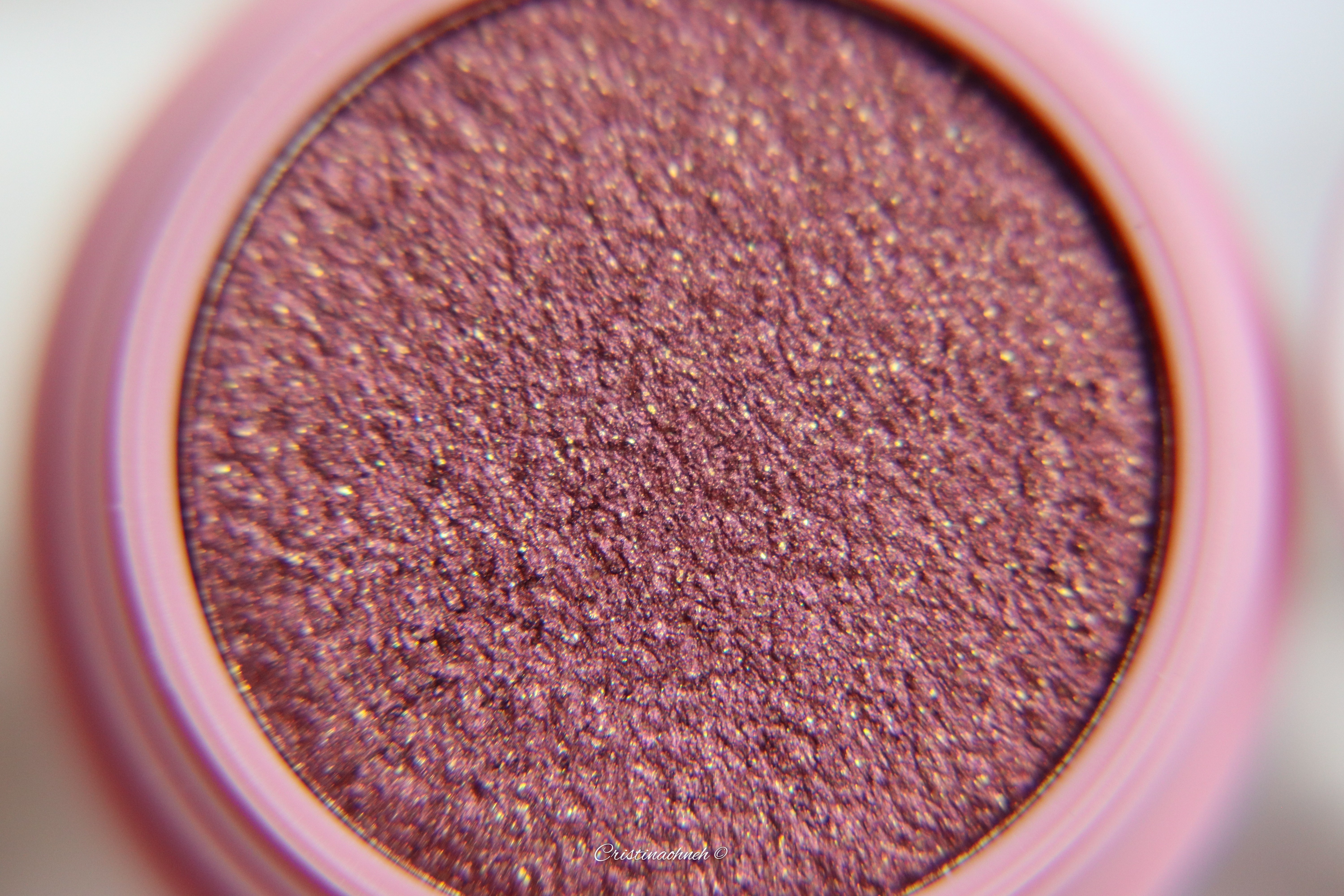 Nahaufnahme eines schimmernden violetten Lidschattens in einer runden Verpackung