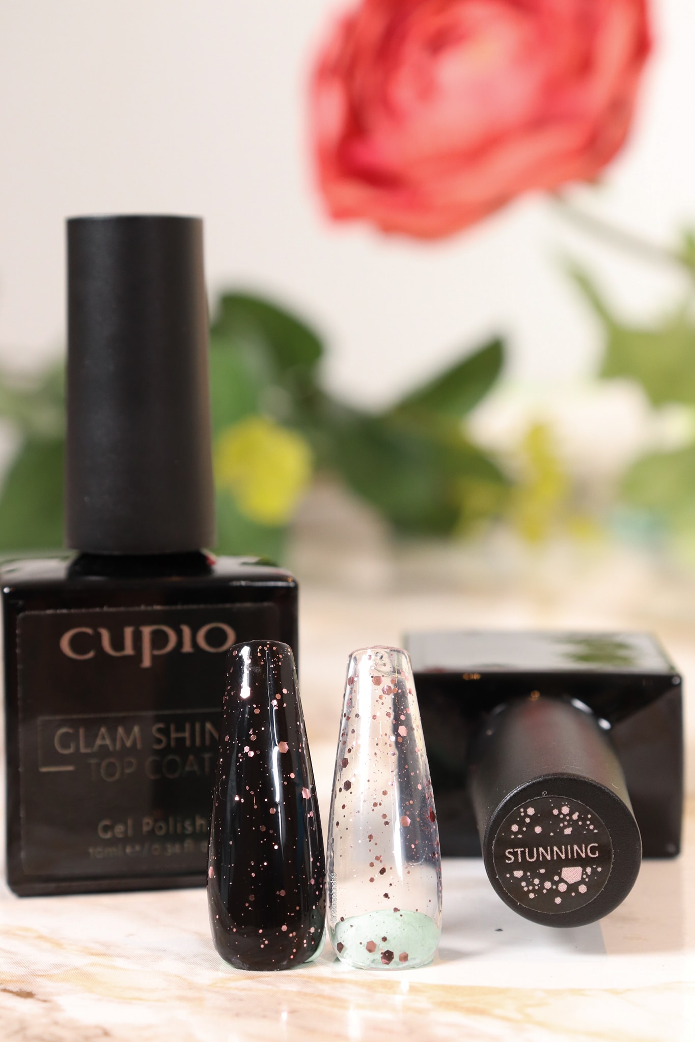 273835338_10221078654898811_6642885295845543069_n Cupio Glam Shine Top Coat und zwei Gel-Lacke in verschiedenen Farben auf einem Tisch.