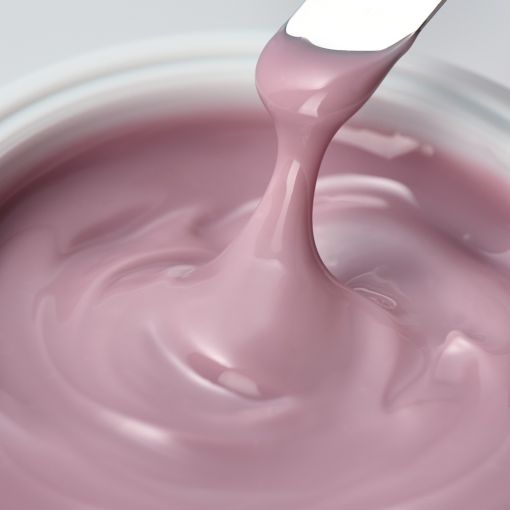 Nahaufnahme einer rosa Creme, die mit einem Spachtel entnommen wird.