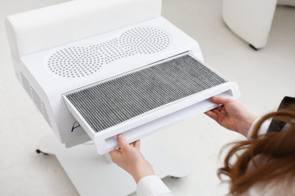 Person zieht einen Filter aus einem Staubabscheider in einem modernen Arbeitsumfeld