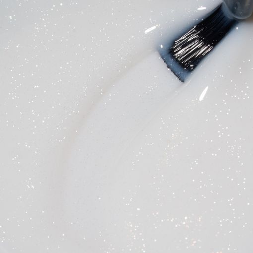 rubber_timeless_frosted_shimmer_c8733_c Nahaufnahme von glitzernder weißer Farbe, die mit einem Pinsel aufgetragen wird