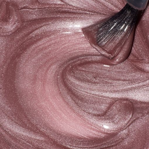 Nahaufnahme von glitzerndem rosa Lippenstift und Pinsel auf einer cremigen Oberfläche