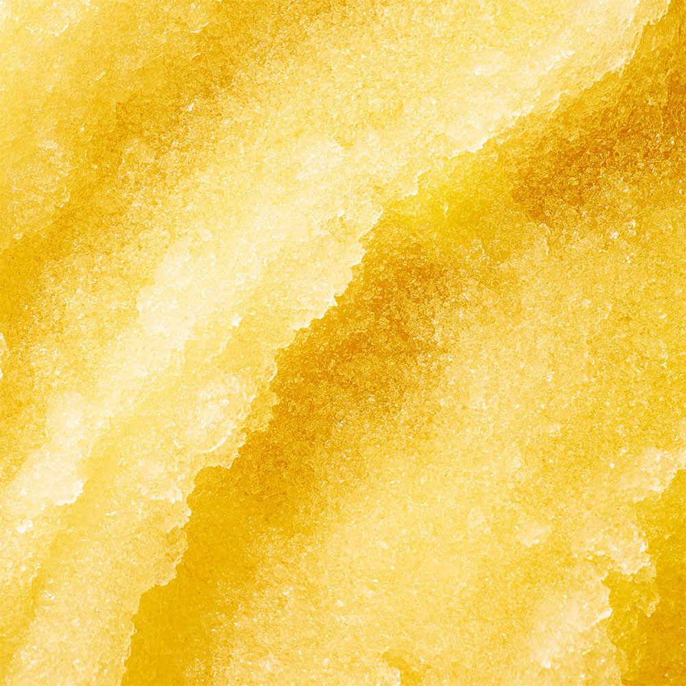 Detailansicht einer gelben Sorbet- oder Fruchteis-Textur als Nahaufnahme mit feiner, kristalliner Oberfläche