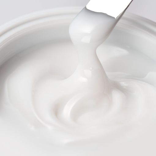 Nahaufnahme einer cremigen, weißen Hautpflegecreme mit Spachtel
