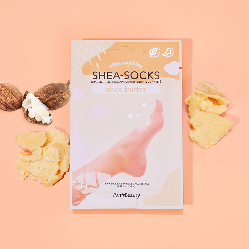 Verpackung der AvryBeauty Shea-Socks mit Sheabutter, umgeben von Sheanüssen und Sheabutter, für intensiv pflegende und beruhigende Fußpflege